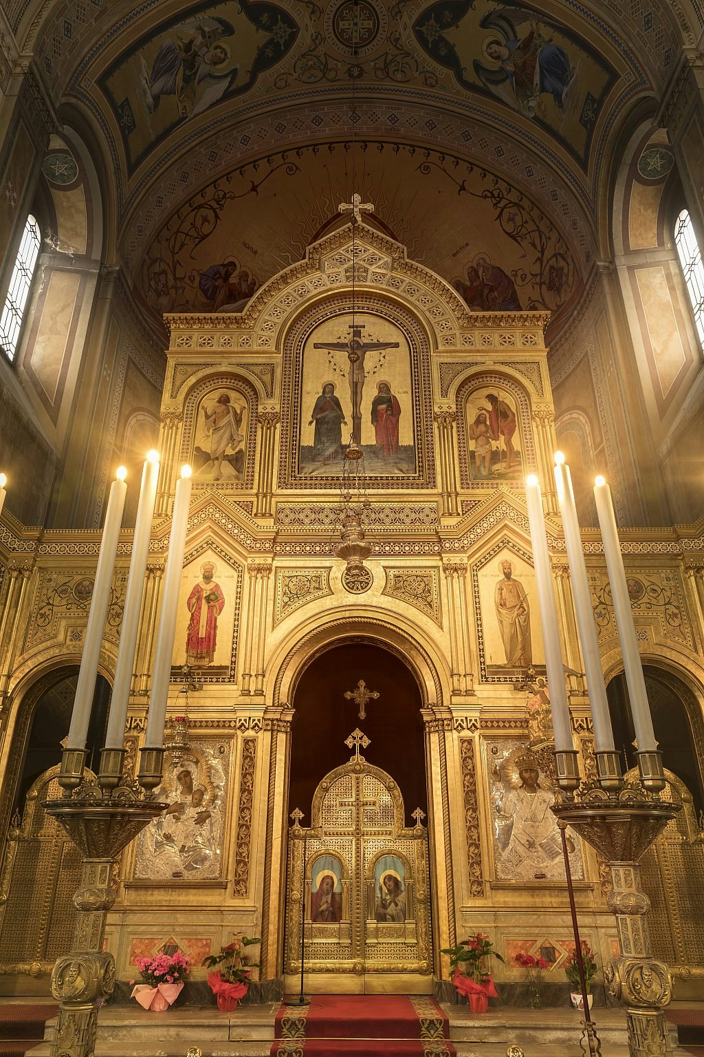 The altar area of an Orthodox church, behind an ornate gold iconostasis (altar screen) bearing religious imagery.